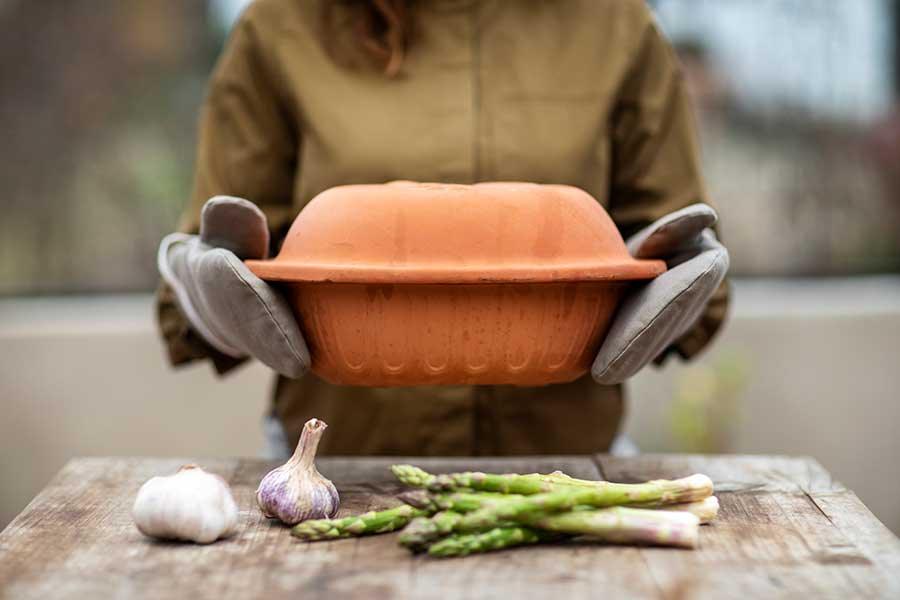 man picking up a pot with oven mitts