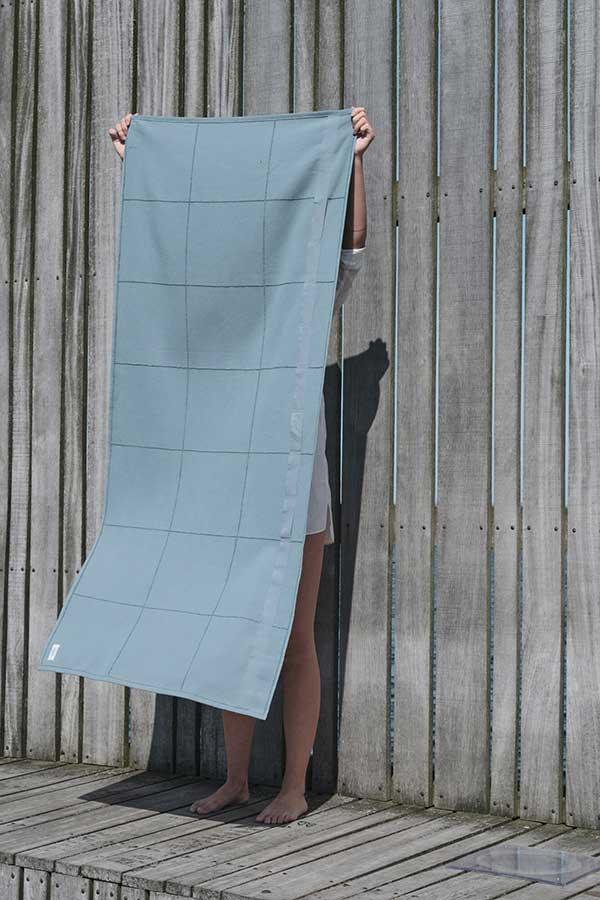 woman holding up a cal towel to wrap by the organic company
