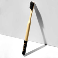 adult bamboo toothbrush leaning on a wall