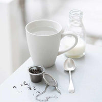 loose tea basket beside mug on table