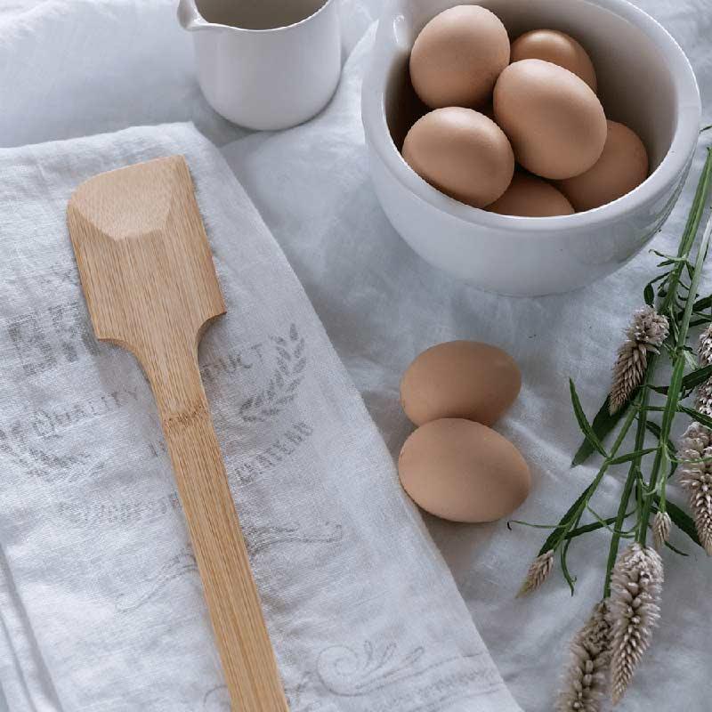 bamboo scraping spatula next to bowl of eggs