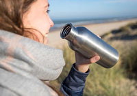 woman drinking from metal water bottle
