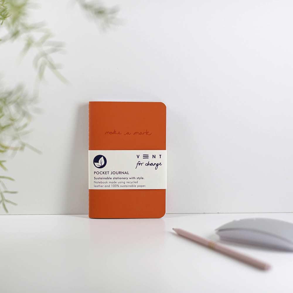 orange recycled leather pocket journal on a desk