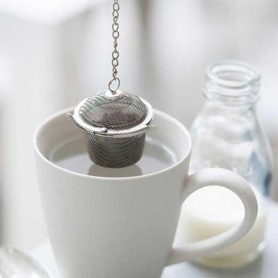 loose tea basket hanging over mug of water
