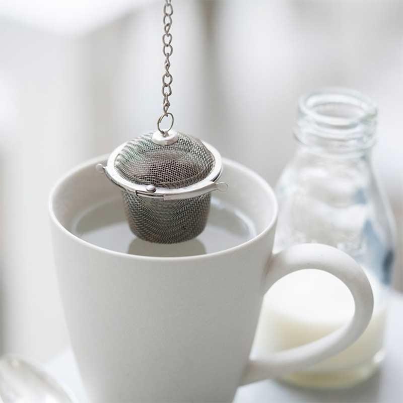 loose tea basket hanging over mug of water