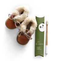 childs bamboo toothbrush next to kids slippers