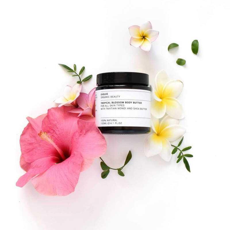 Evolve Tropical Blossom Organic Body Butter next to flowers